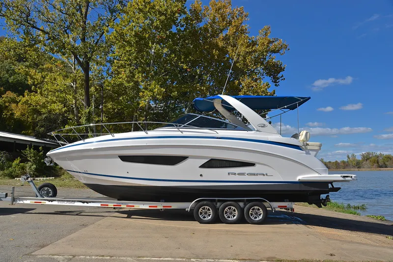 Slide: The Image of 2018 Regal 33 Express boat on trailer by a lake, under clear blue sky. - 14