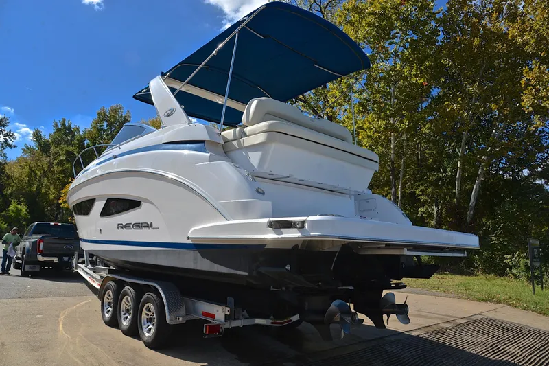 Slide: The Image of 2018 Regal 33 Express boat on trailer, parked near trees under blue sky. - 15