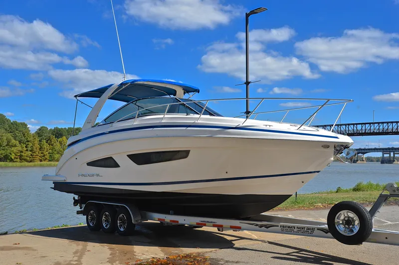 Slide: The Image of 2018 Regal 33 Express boat on trailer by riverside, under blue sky. - 19