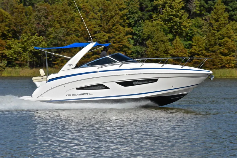 Slide: The Image of 2018 Regal 33 Express boat cruising on a lake with lush green trees in the background. - 3