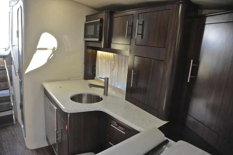 Slide: The Image of 2018 Regal 33 Express yacht interior kitchen with dark wood cabinets and modern appliances. - 36