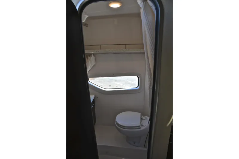 Slide: The Image of 2018 Regal 33 Express boat bathroom interior with toilet and window. - 49