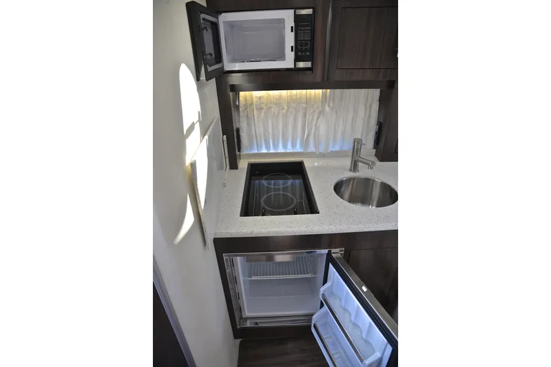 Slide: The Image of 2018 Regal 33 Express yacht kitchen with microwave, stove, sink, and fridge. - 51