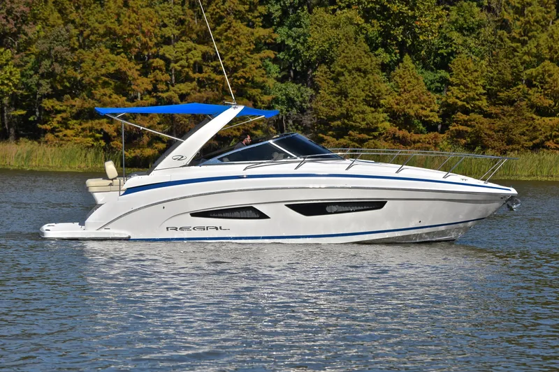 Slide: The Image of 2018 Regal 33 Express boat cruising on a serene lake with lush green trees. - 8