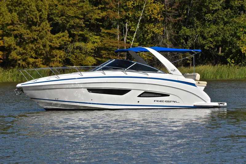 Slide: The Image of 2018 Regal 33 Express boat cruising on a serene lake with lush green trees. - 9