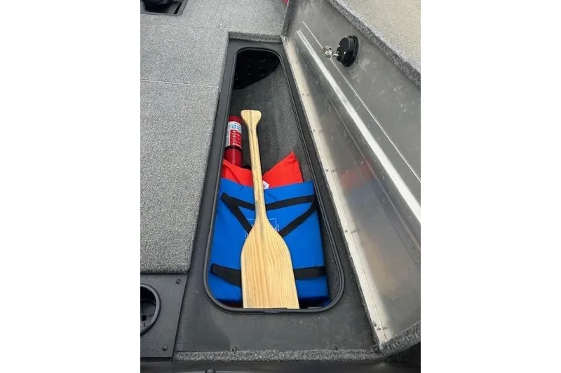 Slide: The Image of 2024 Tracker Pro Team 175 TXW storage compartment with paddle, life jacket, and fire extinguisher. - 11