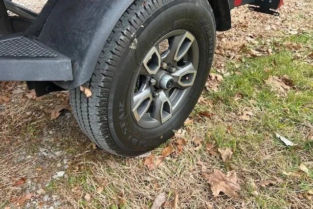 Slide: The Image of 2024 Tracker Pro Team 175 TXW trailer wheel on grass and leaves. - 7