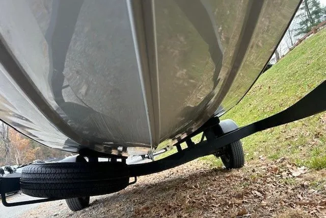 Slide: The Image of 2024 Tracker Pro Team 175 TXW boat on trailer, viewed from below, parked on grassy area. - 9