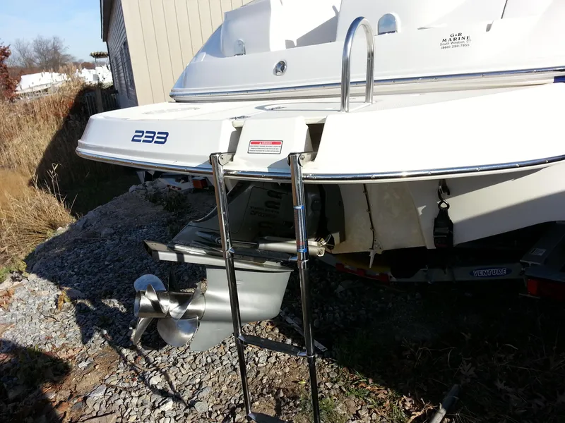 Slide: The Image of 2006 Monterey 233 Explorer boat stern with ladder and propeller, parked on gravel. - 10
