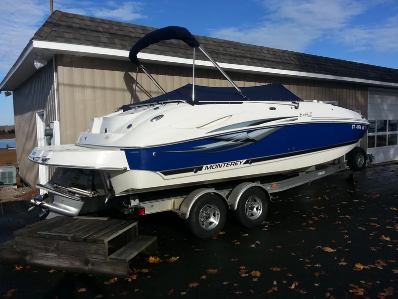 Slide: The Image of 2006 Monterey 233 Explorer boat on trailer, parked beside a building. - 2