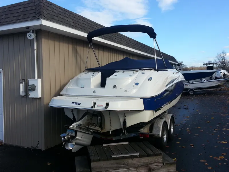 Slide: The Image of 2006 Monterey 233 Explorer boat on trailer near a building, under a clear sky. - 3