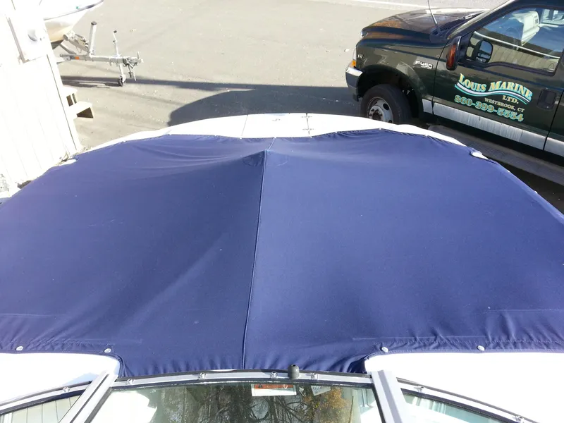 Slide: The Image of 2006 Monterey 233 Explorer boat with blue canvas cover in a marina setting. - 30