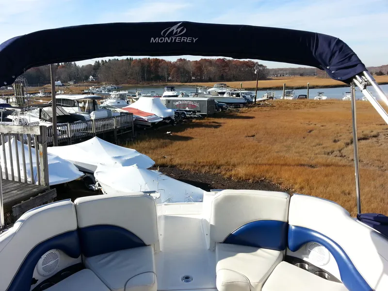 Slide: The Image of 2006 Monterey 233 Explorer boat docked near a scenic marina with covered vessels. - 31