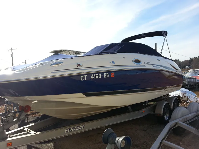 Slide: The Image of 2006 Monterey 233 Explorer boat on trailer, blue and white, with cover, parked outdoors. - 4