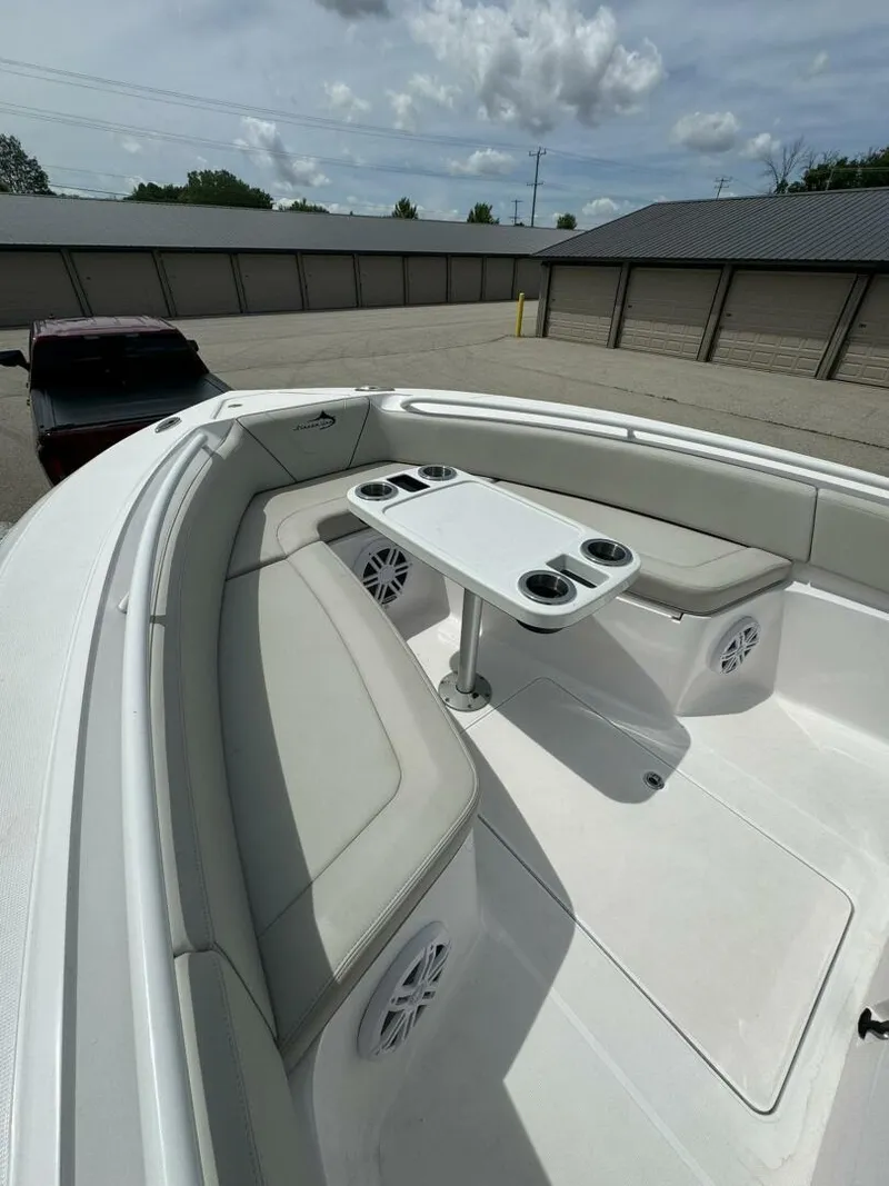 Slide: The Image of 2022 Streamline Center Console boat with cushioned seating and table, parked outdoors. - 16