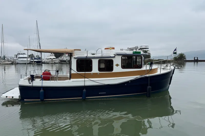 Slide: The Image of 2016 Ranger Tugs R-27 boat docked in a marina with overcast skies. - 0