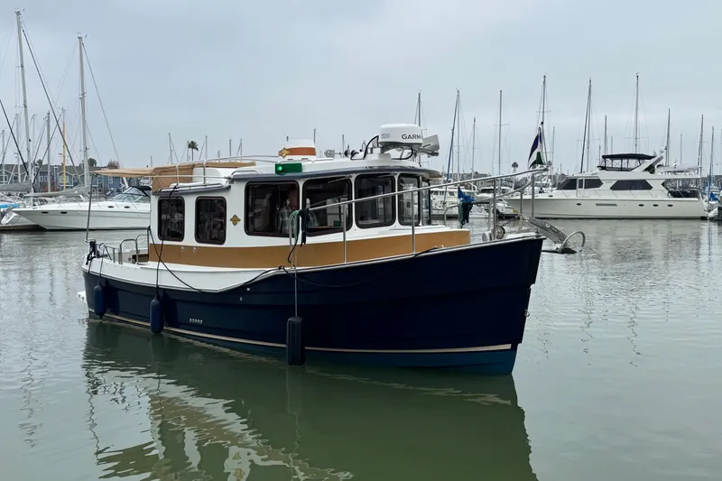 Slide: The Image of 2016 Ranger Tugs R-27 boat docked in a marina with sailboats in the background. - 2