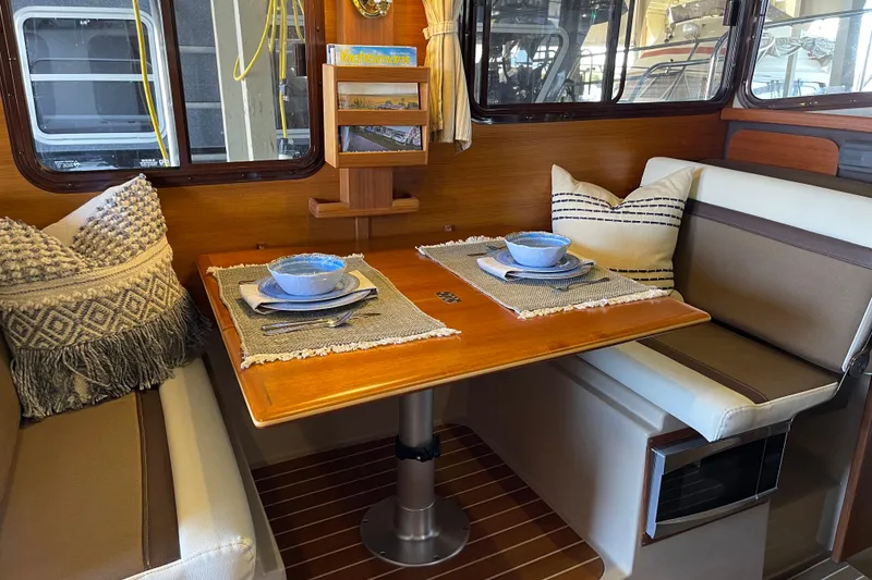 Slide: The Image of Cozy dining area in 2016 Ranger Tugs R-27 with elegant table setting and cushions. - 24