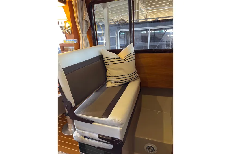 Slide: The Image of Interior seating of 2016 Ranger Tugs R-27 boat with striped cushion and wooden accents. - 26