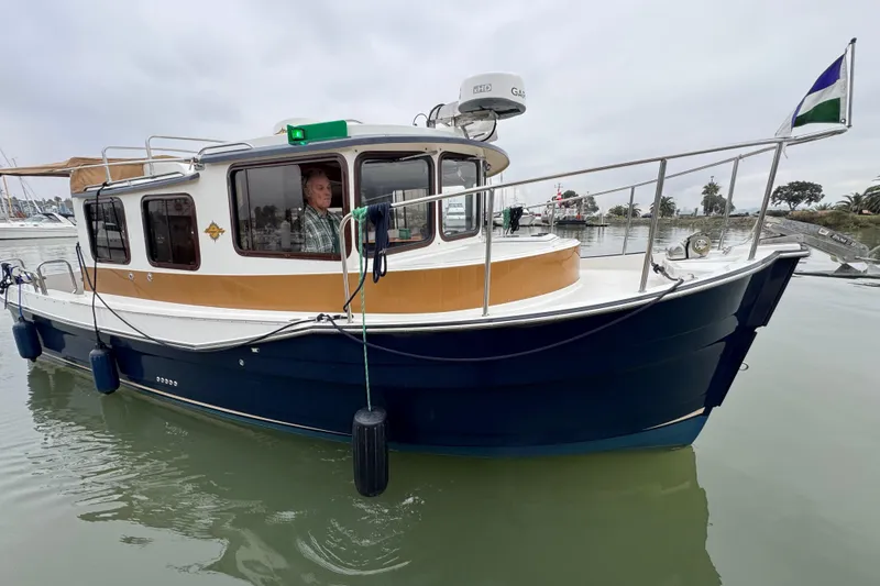 Slide: The Image of 2016 Ranger Tugs R-27 boat docked in calm waters, with a person inside. - 3