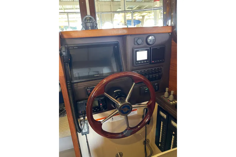 Slide: The Image of 2016 Ranger Tugs R-27 helm with wooden steering wheel and navigation controls. - 30