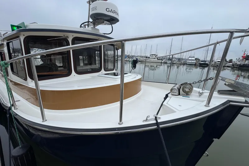 Slide: The Image of 2016 Ranger Tugs R-27 boat docked in a marina, featuring a sleek design and modern equipment. - 38