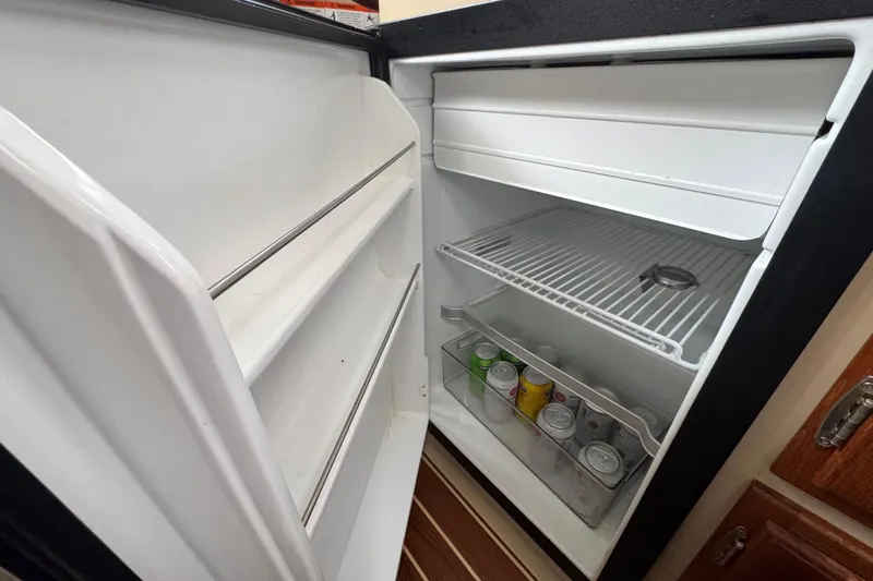 Slide: The Image of Open refrigerator inside 2016 Ranger Tugs R-27 boat, stocked with canned beverages. - 51