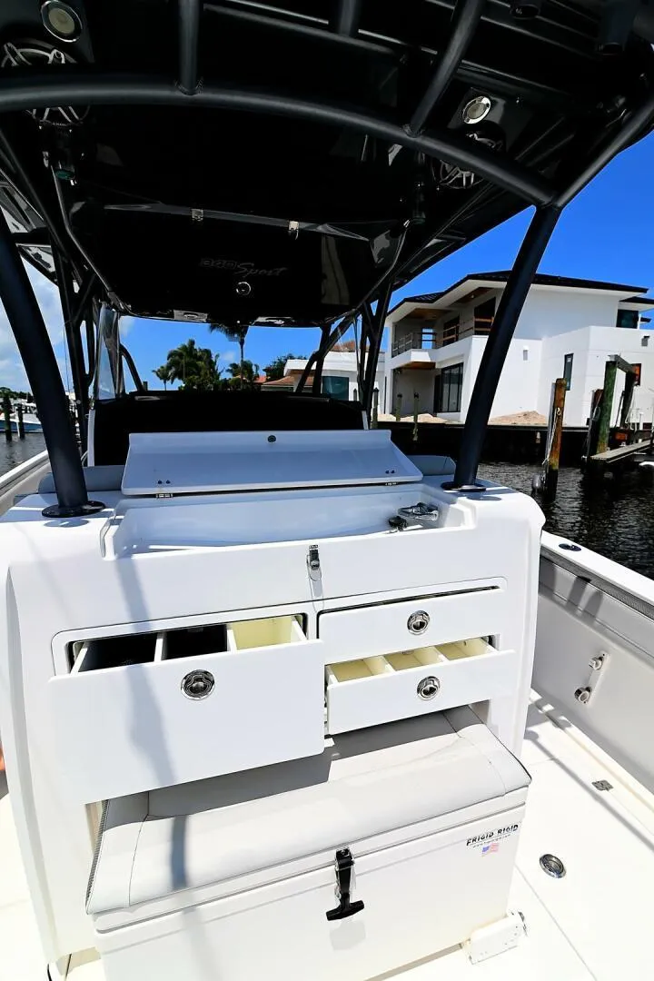 Slide: The Image of 2020 Nor-Tech 340 Sport boat with open storage compartments, docked near waterfront homes. - 21
