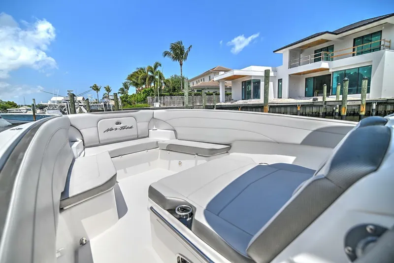 Slide: The Image of 2020 Nor-Tech 340 Sport boat with luxurious seating, docked near modern waterfront homes. - 32