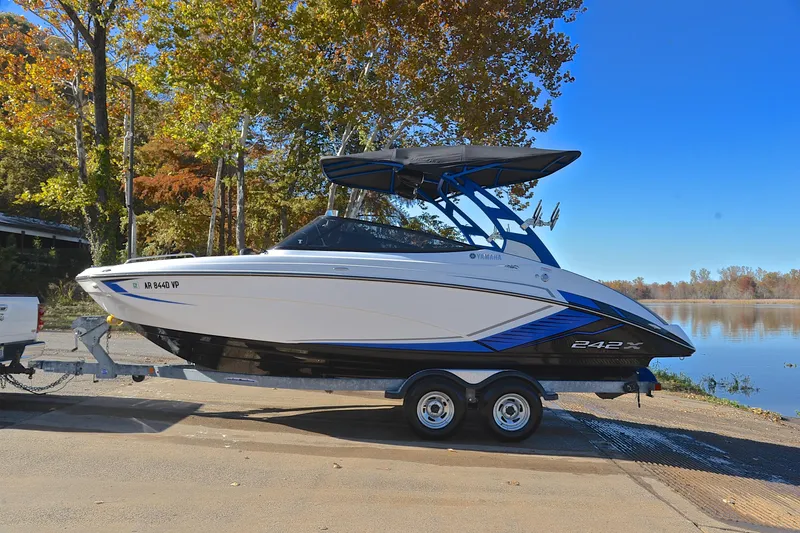 Slide: The Image of 2018 Yamaha Boats 242X on trailer by a scenic lake with autumn trees. - 11