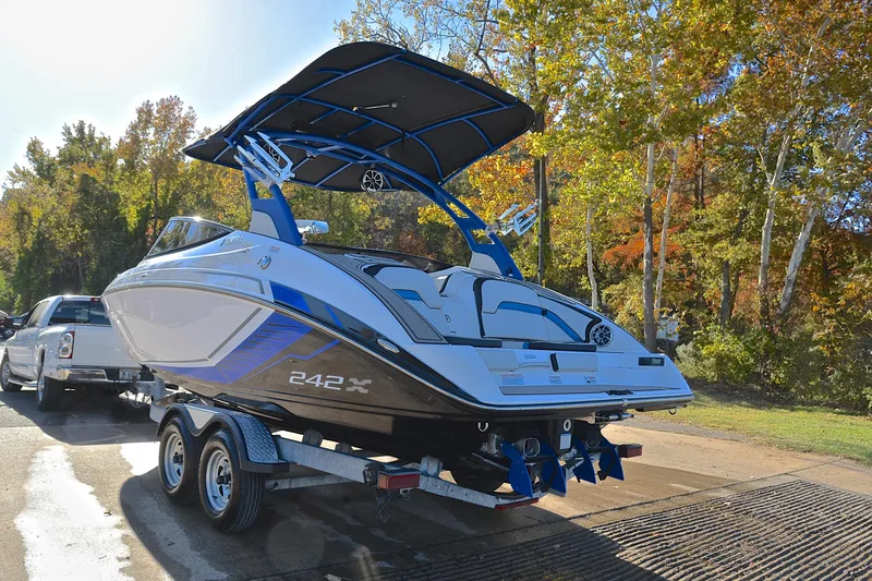 Slide: The Image of 2018 Yamaha Boats 242X on trailer, parked near autumn trees. - 12