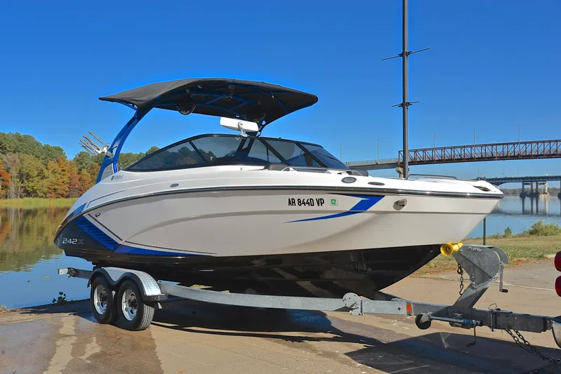 Slide: The Image of 2018 Yamaha Boats 242X on trailer by a scenic lake and bridge. - 16