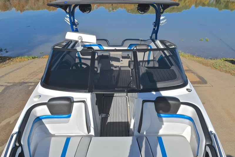 Slide: The Image of 2018 Yamaha Boats 242X interior with blue accents, docked by a calm lake. - 20