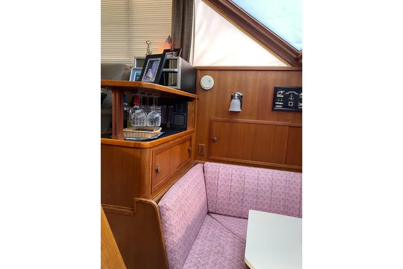 Slide: The Image of 1986 Chris-Craft 426 Catalina interior with wood paneling and cozy seating area. - 12