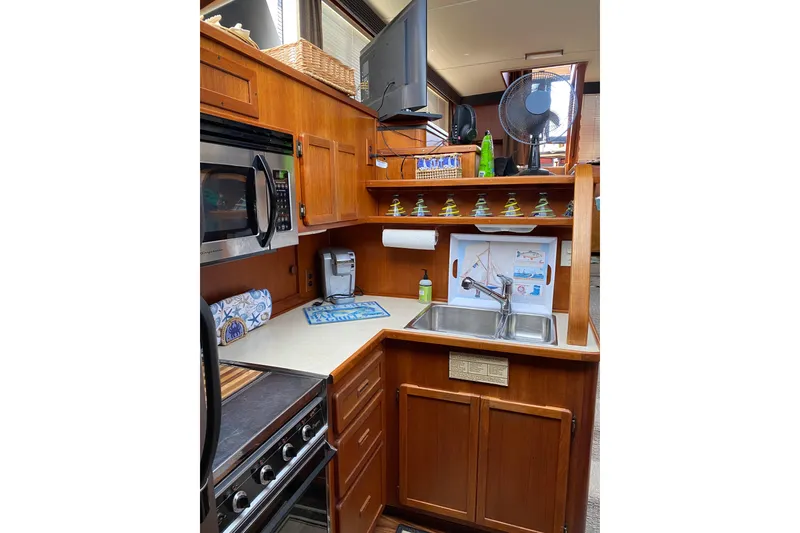 Slide: The Image of 1986 Chris-Craft 426 Catalina yacht kitchen with wooden cabinets and modern appliances. - 16