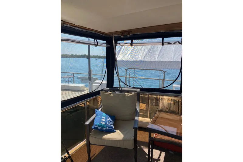 Slide: The Image of 1986 Chris-Craft 426 Catalina interior with lake view, featuring a cozy chair and table. - 29