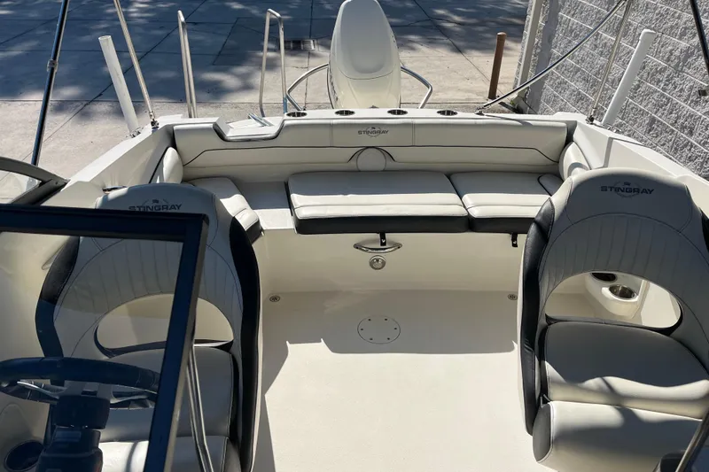 Slide: The Image of 2020 Stingray 201DS boat interior with seating and steering wheel, docked outdoors. - 28
