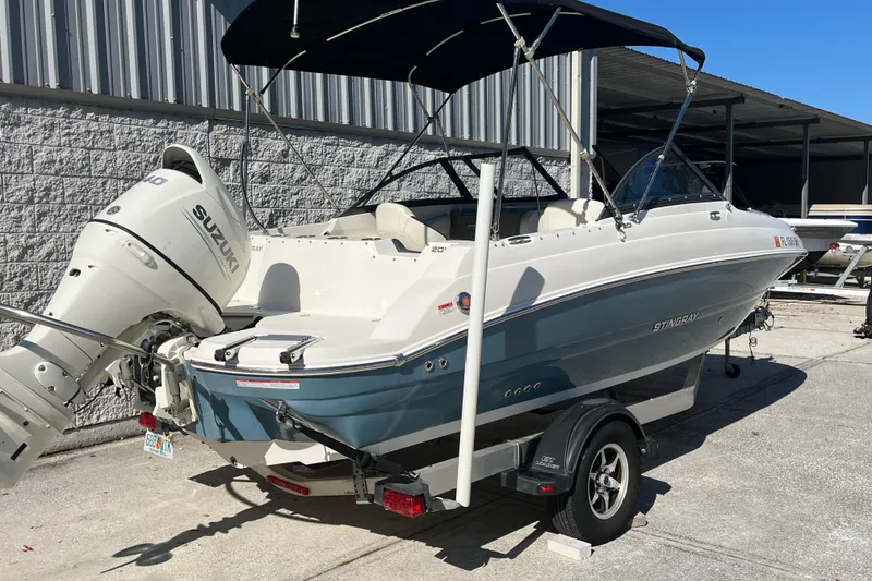 Slide: The Image of 2020 Stingray 201DS boat with Suzuki outboard motor on trailer, parked outdoors. - 3