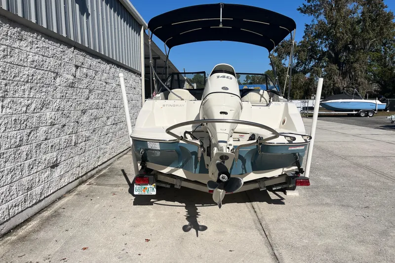 Slide: The Image of 2020 Stingray 201DS boat with outboard motor, parked outdoors under blue sky. - 5