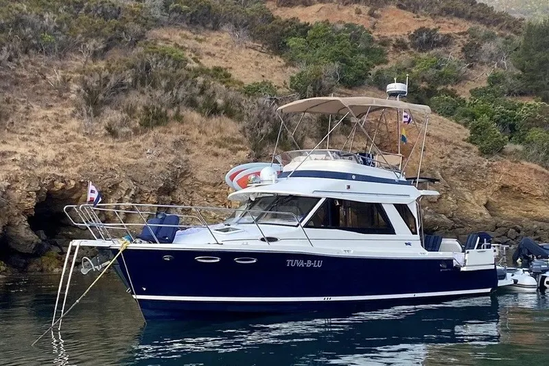 The Image of 2015 Cutwater 30 Command Bridge yacht anchored near rocky shoreline. - 0