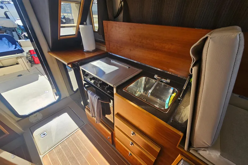 Slide: The Image of Interior of 2015 Cutwater 30 Command Bridge, featuring a compact kitchen with stove and sink. - 30