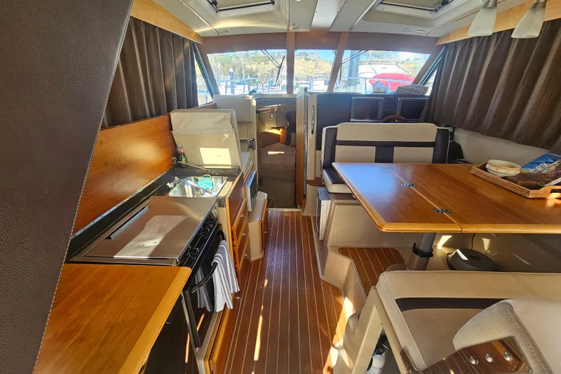 Slide: The Image of Interior of 2015 Cutwater 30 Command Bridge with wood finishes and dining area. - 37