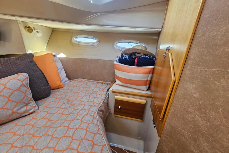 Slide: The Image of Cozy cabin interior of 2015 Cutwater 30 Command Bridge with striped bedding and storage. - 50