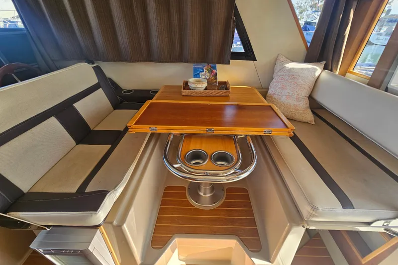 Slide: The Image of Interior of 2015 Cutwater 30 Command Bridge with cozy seating and wooden table. - 53