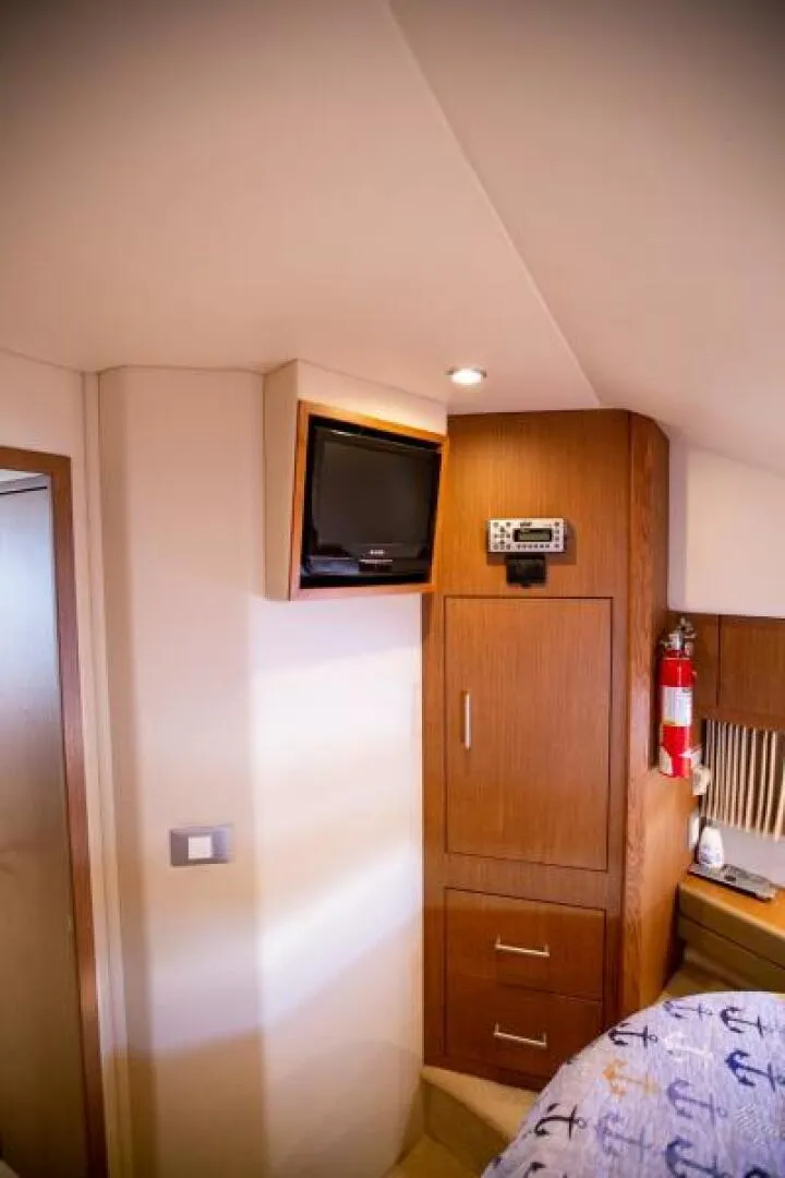 Slide: The Image of Interior of 2012 Carver Sojourn yacht with TV, wooden cabinets, and nautical-themed bedding. - 11