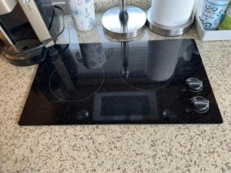 Slide: The Image of Modern black glass cooktop on a granite countertop with kitchen appliances nearby. - 29
