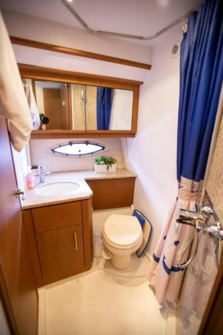 Slide: The Image of 2012 Carver Sojourn bathroom with wooden cabinetry, mirror, sink, toilet, and blue shower curtain. - 9