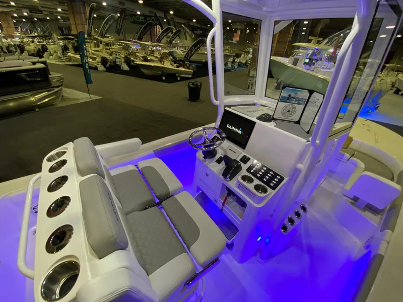 Slide: The Image of 2025 Caymas 26 HB boat interior with illuminated console and seating at a boat show. - 6