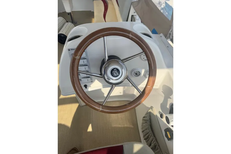 Slide: The Image of Steering wheel of a 2019 ElectraCraft 182TR boat, featuring a wooden finish. - 11