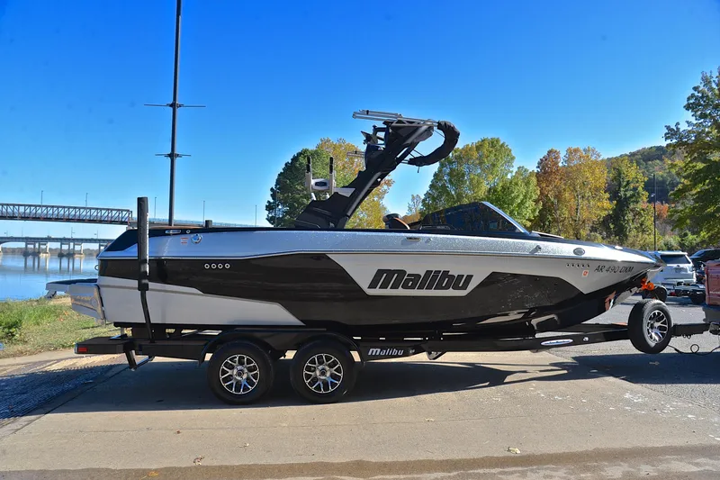 Slide: The Image of 2023 Malibu Wakesetter 23 LSV boat on trailer by riverside, clear blue sky. - 15